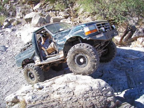1991 Ford Bronco - Modified Ford Bronco navigates a rocky off-road trail with its doors removed.