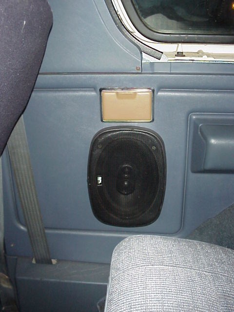 1989 Ford Bronco - Interior close-up of a blue rear quarter trim panel in a truck or SUV, showing a black 6x9-style oval speaker with a mesh grille mounted in…