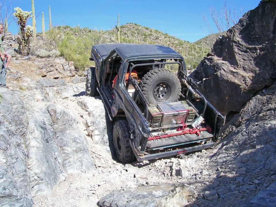 Black off-road SUV with spare tire on back navigating a rocky canyon