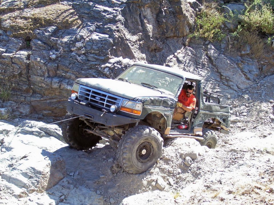 1991 Ford Bronco navigating a steep, rocky trail with a winch line attached