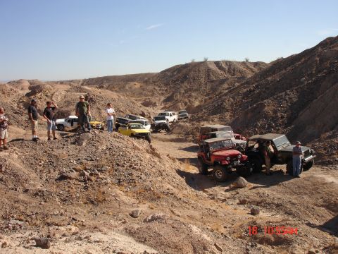 1996 Ford Bronco - Several off-road vehicles are gathered in a desert canyon with people observing.