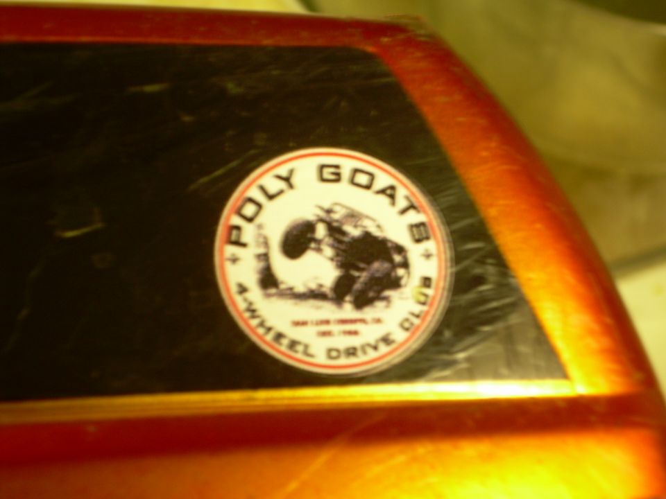 Orange vehicle with a 'Poly Goats 4-Wheel Drive Club' sticker on the window