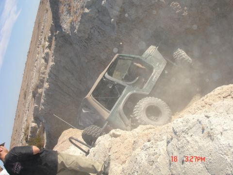 1996 Ford Bronco - A Jeep Wrangler is stuck on a steep, dusty incline, with onlookers observing the situation.