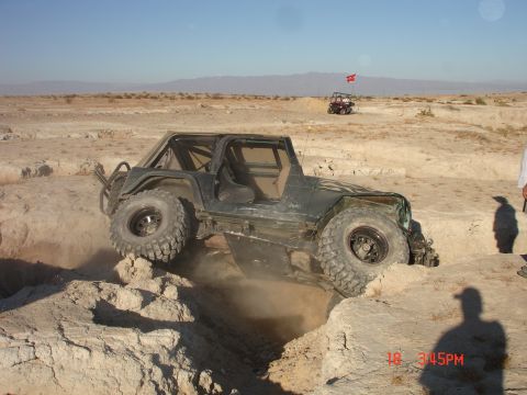 1996 Ford Bronco - A Jeep Wrangler navigates a challenging off-road course in a desert landscape.