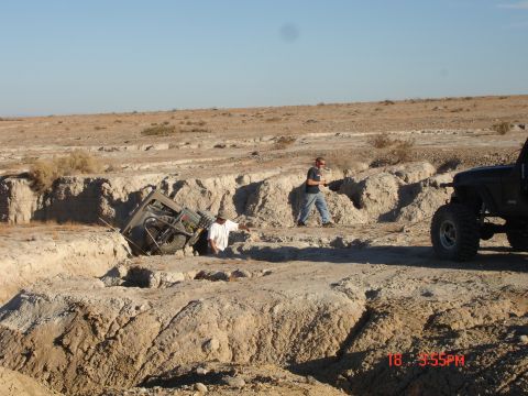 1996 Ford Bronco - Two people attempt to free an off-road vehicle that has become stuck in a deep ditch in a desert landscape.