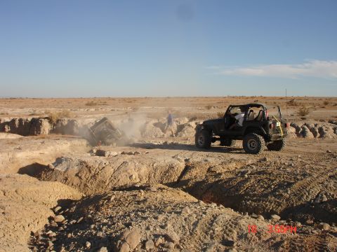 1996 Ford Bronco - Two Jeeps in a desert setting, one is stuck in a deep ditch.