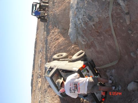 1996 Ford Bronco - A group of off-road vehicles navigate a steep, rocky terrain, with one Bronco overturned.
