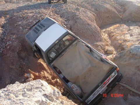 1996 Ford Bronco - A truck is stuck in a ditch, with another vehicle attempting to pull it out with a tow rope.