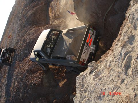 1996 Ford Bronco - Two off-road trucks are stuck on a steep rocky incline, one being pulled by a winch.