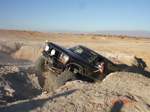1996 Ford Bronco - A 1996 Ford Bronco maneuvers through a challenging off-road terrain with steep dirt walls.