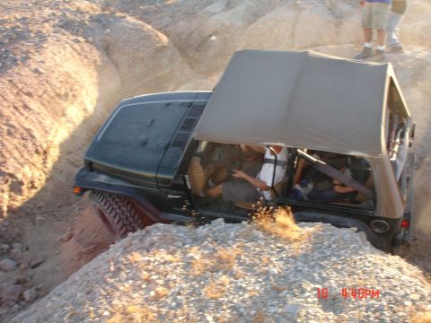 1996 Ford Bronco - A Jeep Wrangler navigates a challenging off-road trail with loose rocks and dirt.