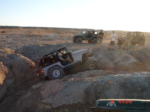 1996 Ford Bronco - Jeeps tackling an off-road trail in a desert environment with spectators watching.
