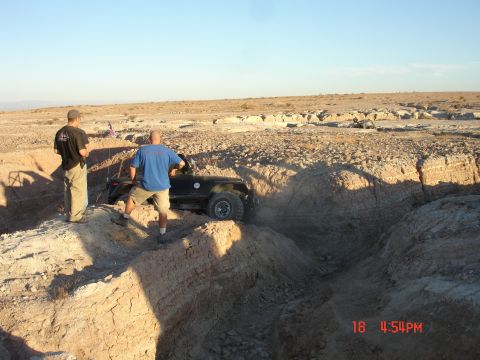 1996 Ford Bronco - Off-road vehicle navigating a challenging trench in a desert environment with two observers.