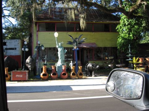 1974 Ford F-100 - A collection of eclectic yard decorations, including a Statue of Liberty replica, are displayed in front of a weathered house.