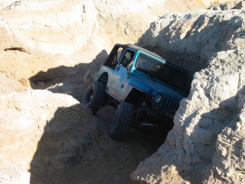 1985 Ford Bronco - A Jeep Wrangler tackles a challenging off-road trail through a rocky gorge.