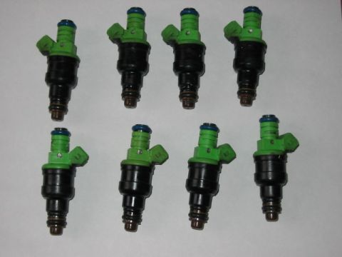 1991 Ford Bronco - A set of eight fuel injectors, each with a black body and green top, are displayed against a plain background.