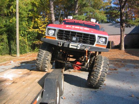 1979 Ford Bronco - This lifted red Ford Bronco is being loaded onto a trailer, showing its front end and large tires.