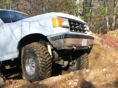 1996 Ford Bronco - This Ford truck is navigating a steep dirt incline with its front wheels turned.