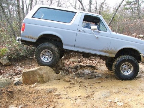 1996 Ford Bronco - This Ford Bronco is shown tackling a challenging off-road course with mud and rocks.
