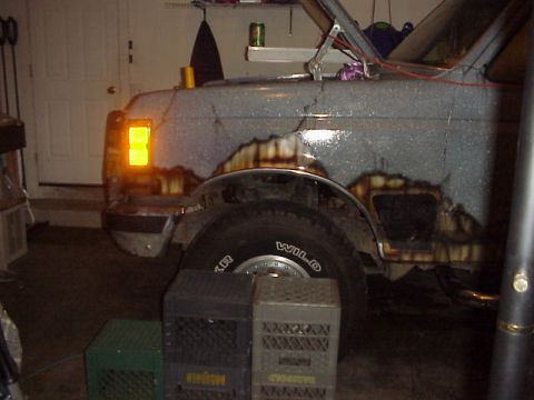 1989 Ford Bronco - The front corner of a Ford Bronco shows significant rust and damage, with the turn signal illuminated.