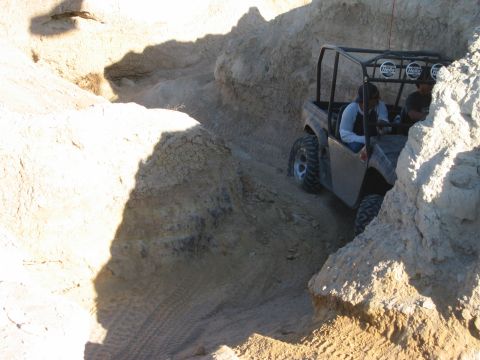1985 Ford Bronco - An off-road vehicle drives through a tight, rocky canyon with people inside.