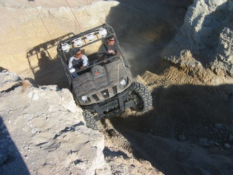 1985 Ford Bronco - This side-by-side vehicle is shown navigating a challenging off-road terrain with steep inclines and dusty conditions.