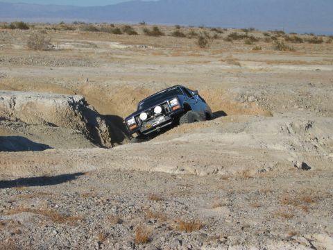 1985 Ford Bronco - This off-road SUV navigates a challenging sandy terrain, demonstrating its capabilities.