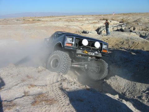 1985 Ford Bronco - This modified SUV, likely from the early 1980s, kicks up dust as it tackles a challenging off-road course.