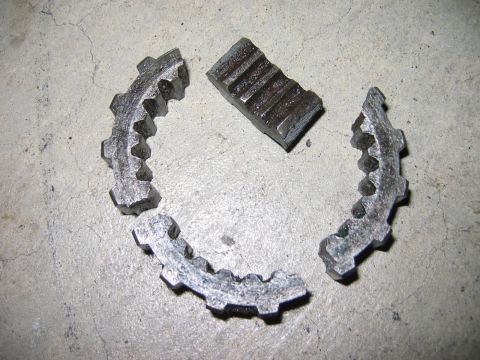 1985 Ford Bronco - Fragmented metal gear pieces scattered on a concrete floor.