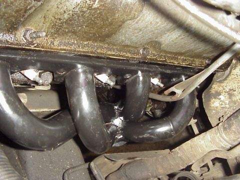 1989 Ford Bronco - Close-up view of an exhaust manifold with black pipes and visible bolts.