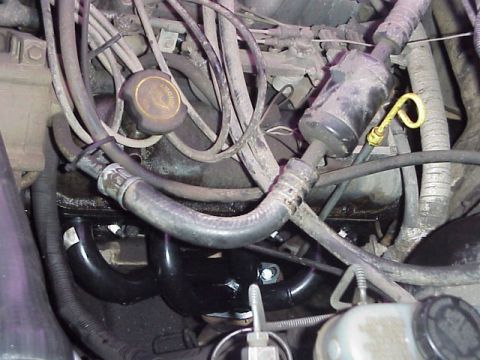 1989 Ford Bronco - Close-up view of engine components, including black headers and numerous hoses and wires.