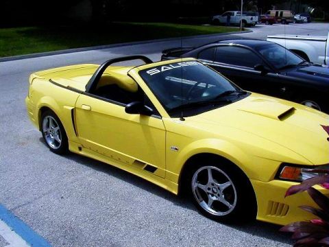 1978 Ford Mustang II - A yellow convertible sports car is parked in a lot next to a black coupe.