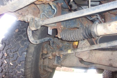 1990 Ford Bronco - Close-up of a vehicle's undercarriage, focusing on suspension and steering parts.