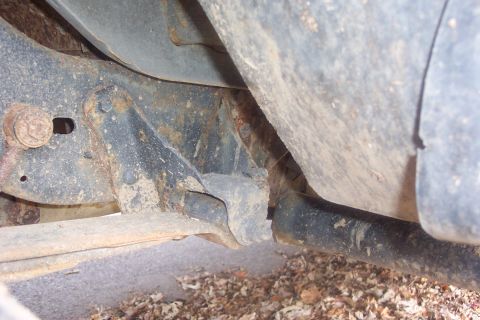 1990 Ford Bronco - Close-up view of heavily rusted vehicle frame and suspension components.