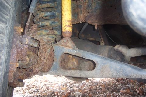 1990 Ford Bronco - The heavily rusted suspension system of a vehicle is shown in detail, with a focus on the shock absorber and springs.