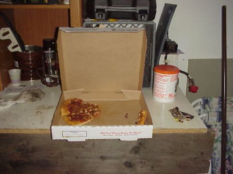 1989 Ford Bronco - A pizza box with a single slice and a few crumbs sits on a table, next to a can and some keys.