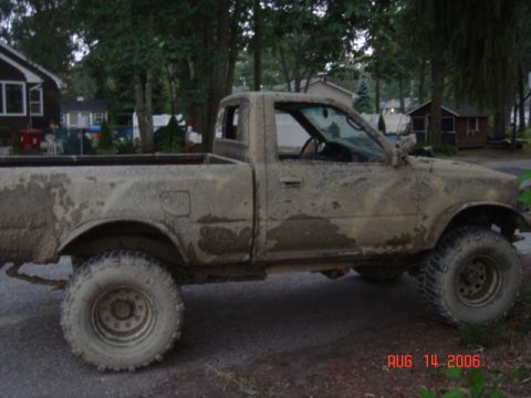 1992 Toyota Tacoma - A heavily muddied pickup truck sits parked on a paved surface, likely after off-road use.
