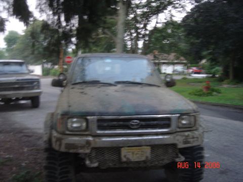 1992 Toyota Tacoma - This Toyota pickup truck, likely from the mid-1990s, is covered in mud and has camouflage paint on its hood and fenders.