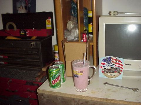 1989 Ford Bronco - A workbench scene tools, drinks, and a computer monitor with a sticker.