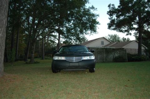 1999 Lincoln Town Car - A black sedan sits on a grassy lawn with houses in the background.