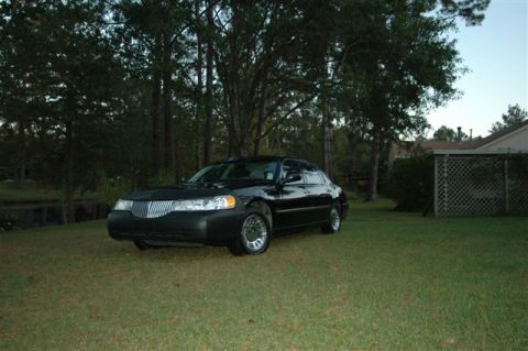 1999 Lincoln Town Car - A black 1999 Lincoln Town Car is parked on a grassy lawn in front of trees and a house.