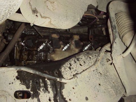 1989 Ford Bronco - Close-up view of an engine's spark plugs and surrounding components, showing signs of oil leakage.