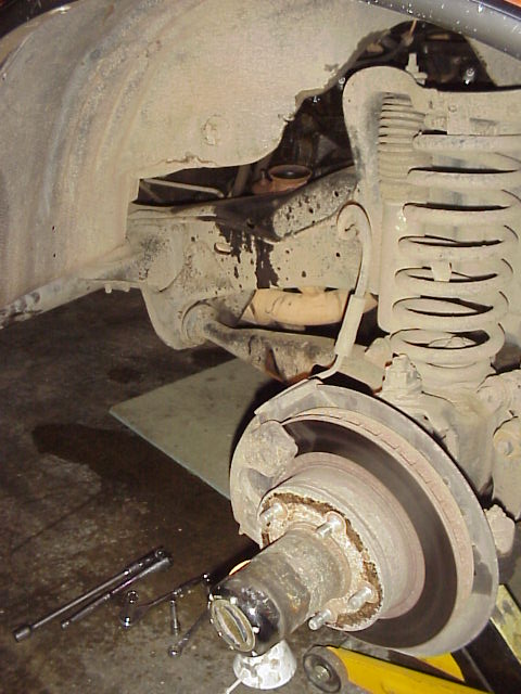 1989 Ford Bronco - Front wheel hub and suspension parts are visible, along with tools on the garage floor.