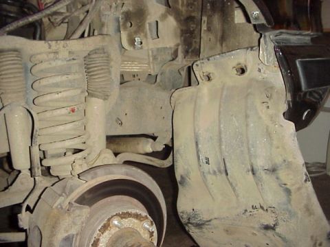 1989 Ford Bronco - This image shows the front suspension and brake assembly of a vehicle, with visible coil springs and a brake rotor.