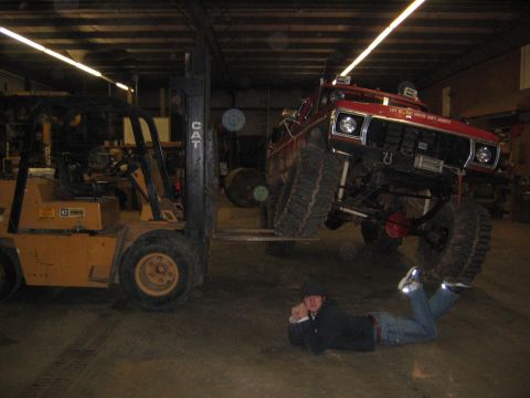 1979 Ford Bronco - Modified 1979 Ford Bronco is lifted by a forklift in a garage, with a person watching.