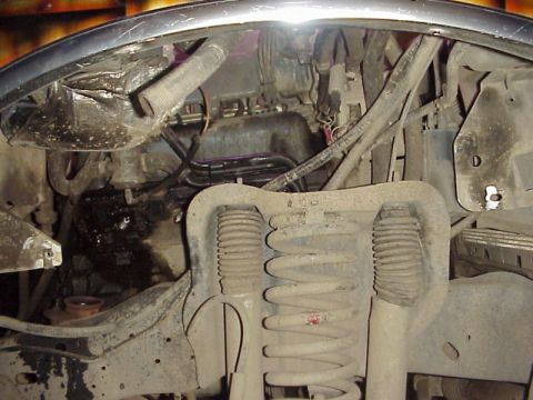 1989 Ford Bronco - Close-up view of a dirty engine bay with suspension components and various hoses.