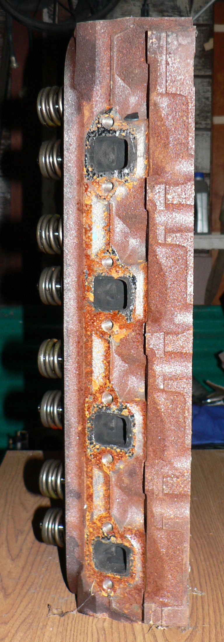 Rusty exhaust side of a cast-iron cylinder head with four carbon-caked square ports