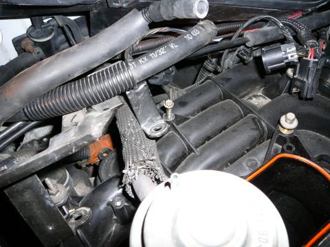 1997 Mercury Grand Marquis - Tight overhead shot into an engine bay showing two exposed bracket bolts standing up out of the black plastic intake manifold runners, one…