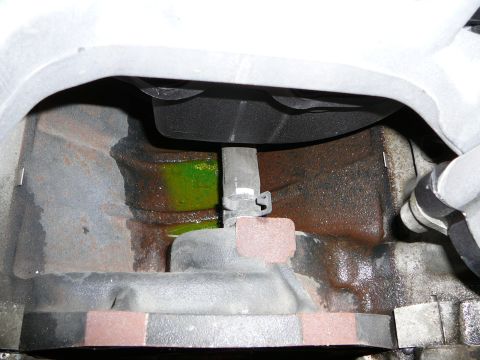 1997 Mercury Grand Marquis - Tight close-up down into an engine valley beneath an intake manifold, showing a coolant crossover hose with a spring-band clamp and bright…