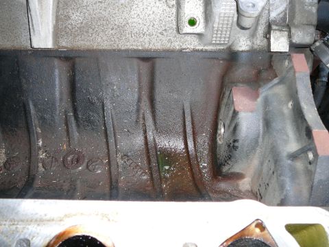 1997 Mercury Grand Marquis - Looking down into the engine valley with the coolant tube and its nipple removed, showing the ribbed cast valley floor stained with coolant…